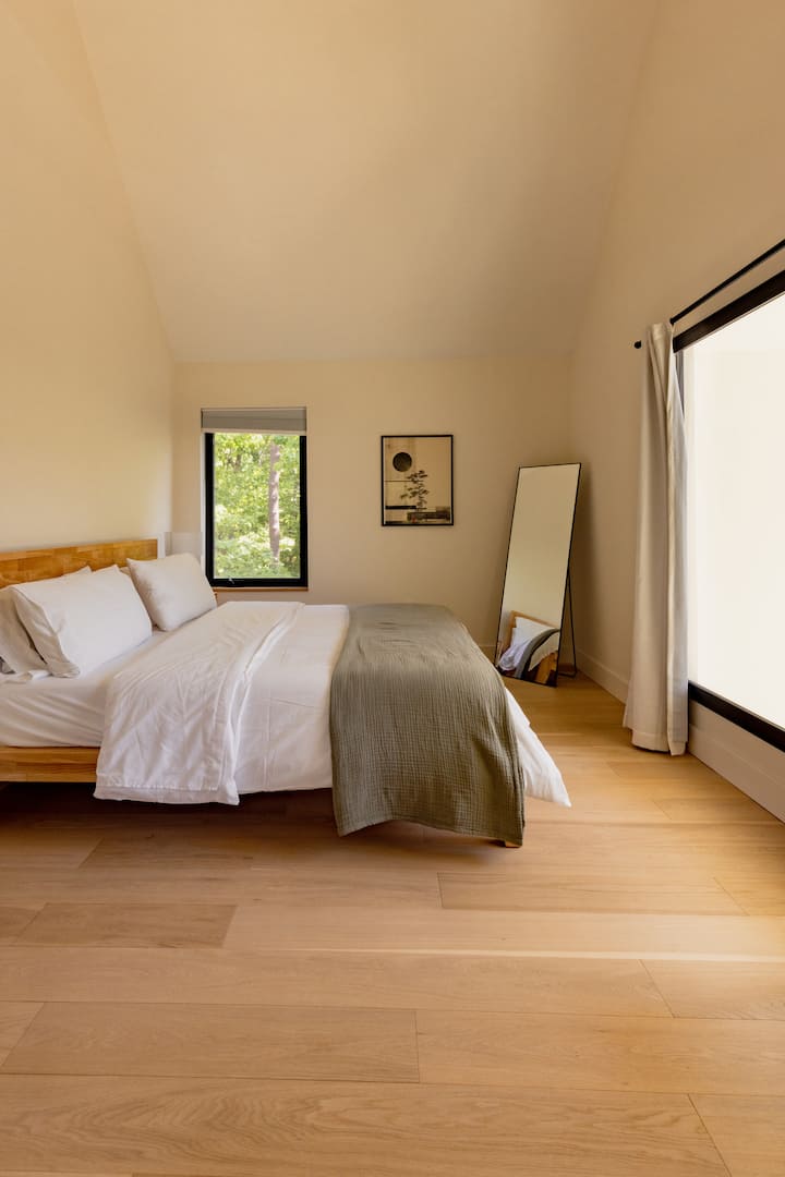 Spacious bedroom with vaulted ceilings and forest views featuring a light-filled bedroom with comfortable king bed.