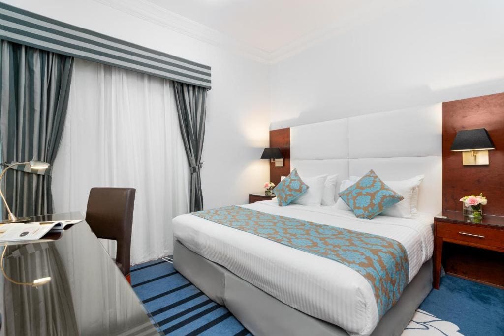 Amplio dormitorio con una acogedora cama tamaño king, mesitas de noche con lámparas a ambos lados, un escritorio de trabajo dedicado y un televisor de pantalla plana. Hay ventanas grandes disponibles en unidades seleccionadas, sujeto a disponibilidad en el momento del registro.