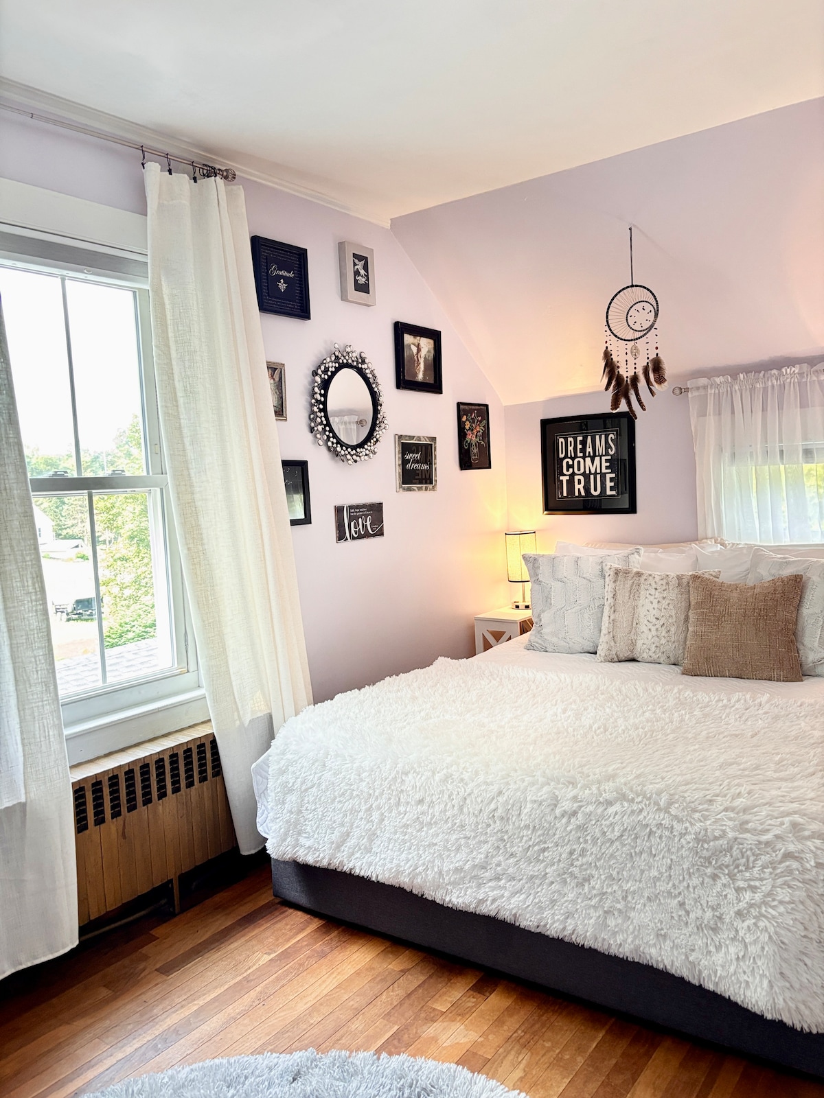 غرفة نوم رئيسية مشرقة وجيدة التهوية مع سرير بحجم كوين، وأغطية سرير فاخرة، وديكور ساحر لليالي المريحة.