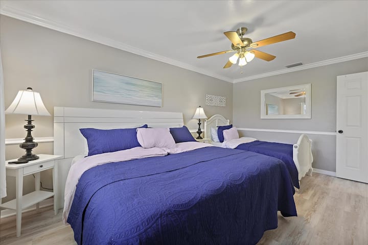 غرفة نوم كبيرة مع سرير كينج وسريرين مفردين،