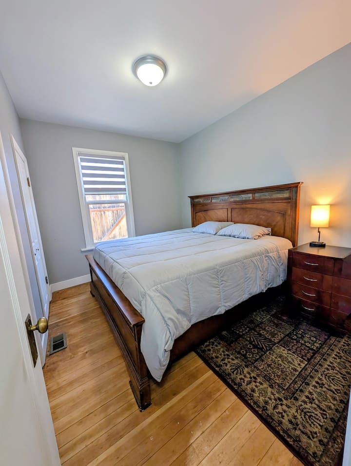 Ამ ოთახში არის დიდი ზომის საწოლი, კარადა, ორი პატარა კომოდი, ღამის სადგამი და ლამპა შტეფსელითა და USB პორტებით.