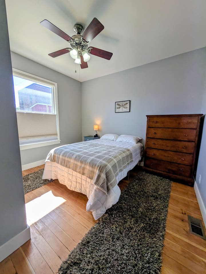 Ამ საძინებელში არის სრული ზომის საწოლი, კომოდი, ტუმბო, სანათი შტეფსელით და USB პორტები და კარადა.