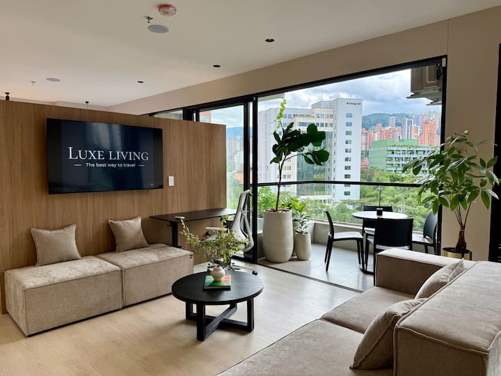 明亮的起居区，配有落地窗、舒适的沙发、Netflix电视以及带人体工程学椅子和显示器的高级可调节电动办公桌。 可直接通往阳台，可欣赏到迷人的城市和山景。