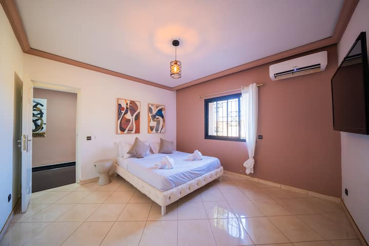 Chumba cha kulala cha kifahari chenye vitanda viwili vya starehe, kuta zenye rangi laini na kiyoyozi kwa ajili ya starehe bora.