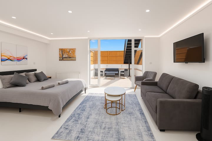 Estudio moderno y luminoso con cama cómoda, sofá, televisión inteligente y terraza privada.