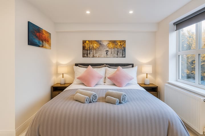 Moderná, minimalistická spálňa s mäkkou posteľou a veľkým oknom plným slnečného svetla.