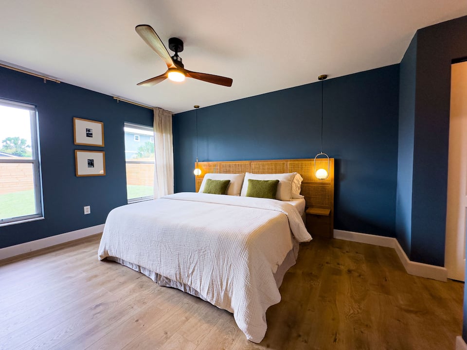 King bedroom with a navy accent wall and ceiling fan