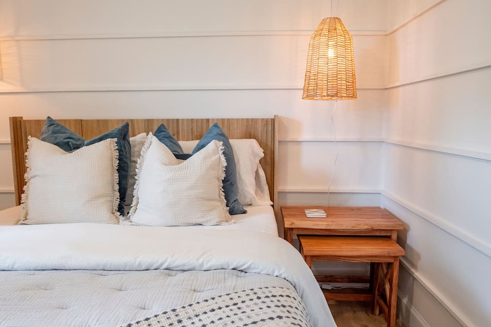 Bedroom 2 with a queen bed, white shiplap walls and rattan pendant lights