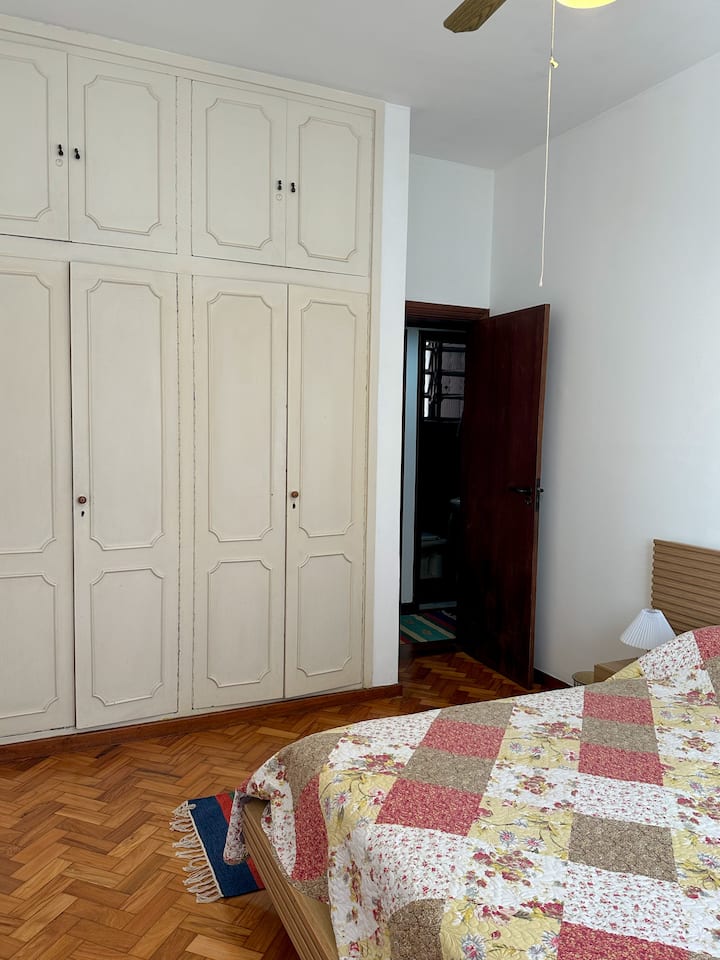 Obratite pažnju na ogromni ormar u ovoj prostoriji, a tu su i iznimno udoban bračni krevet, veliki prozor, stropni ventilator, noćni ormarići sa svjetiljkama i veliki prozor sa zavjesama koje zatamnjuju prostoriju.