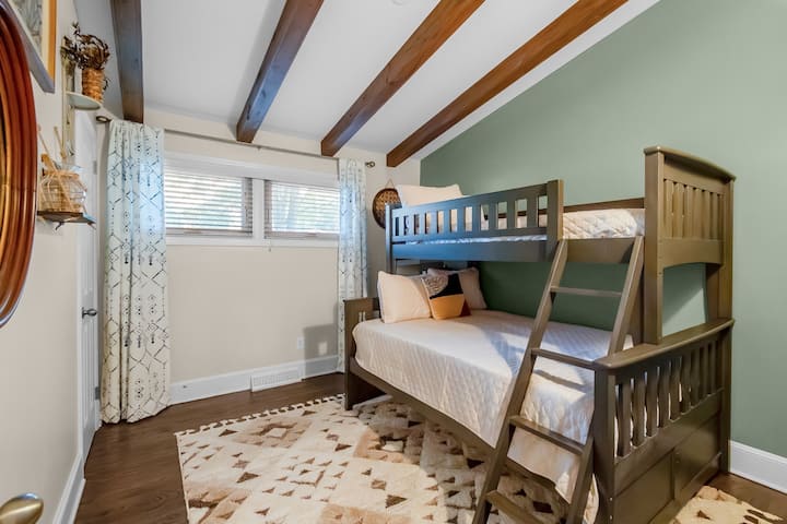 Уютна спалня с двуетажно легло, сводести таванни греди и стилен декор – идеално за деца, приятели или малки семейства.