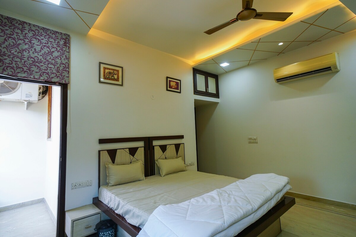 Elegante dormitorio con cama tamaño queen, aire acondicionado, ventilador de techo e iluminación moderna con balcón privado para aire fresco y relajación.