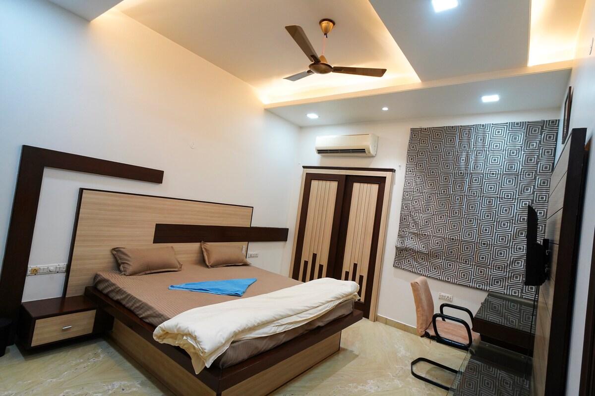 Dormitorio moderno con cama doble, aire acondicionado, ventilador de techo, amplio espacio de almacenamiento y cómodos asientos diseñados para la relajación y el sueño reparador.