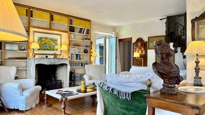 غرفة معيشة بها أريكتان وكرسيان بذراعين ومواد للقراءة وإمكانية الوصول إلى المطبخ وغرفة الطعام