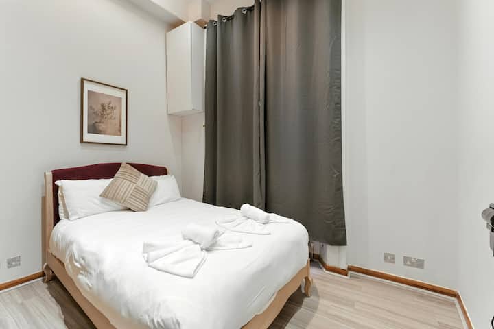 חדר שינה נעים עם מיטה זוגית נוחה, מצעים נקיים ותאורה רכה. ארונות עץ גדולים מספקים שפע של מקום אחסון, מושלם לשהייה רגועה.