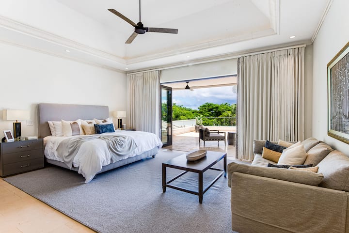 Impressionant dormitori principal amb aire condicionat, ventilador de sostre, balcó, vestidor i un llit extragrande.