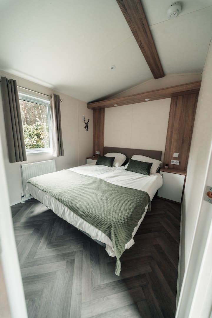 Rustige en comfortabele slaapkamer met een tweepersoonsbed, natuurlijk licht door het raam.