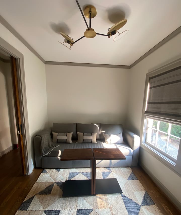 Una sala de estar flexible: proporciona el lugar perfecto para una maratón de cine/deportes, ya que esta habitación proporciona cortinas romanas que oscurecen la habitación para un huésped adicional, ya que el sofá proporciona otra opción de cama completa para dormir.