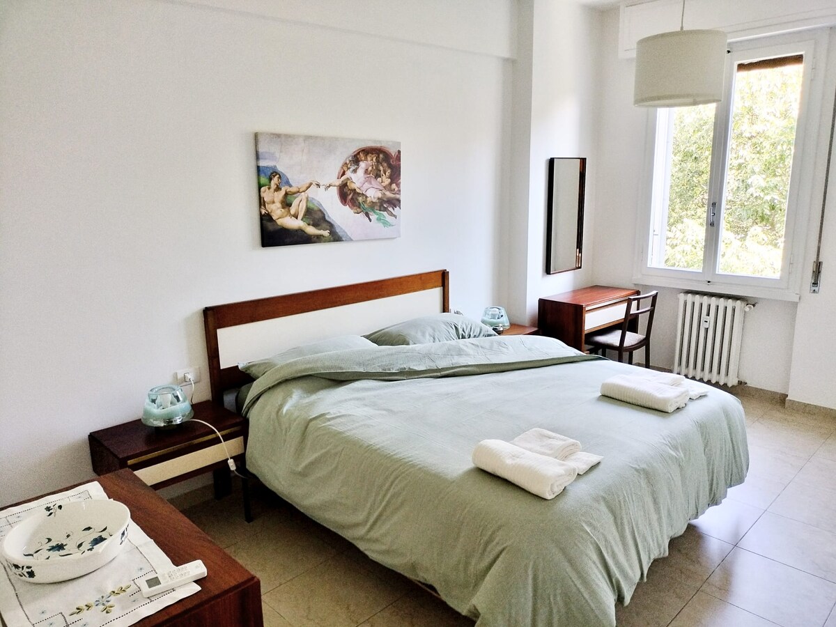 Elegante, comfortabele en ontspannende slaapkamer: witte muren, beige travertijn porseleinen steengoed vloer, bruin meubilair, dameskaptafel, twee grote spiegels, comfortabele en ruime witte kledingkast.   