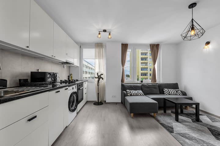 Дневен простор со отворен концепт со удобен кауч, трпезариски простор и целосно опремена кујна | Резервирајте сега со RENTUJEMY.COM