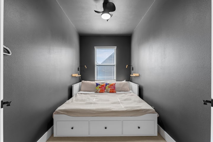 Уютна спалня с голямо легло, меланхолични тонове и естествена светлина – идеална за отдих след разглеждане на Хюстън.