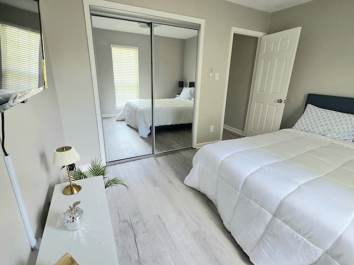 מיטת קווין סייז עם דלתות ארון עם מראה.  טלוויזיה חכמה המורכבת על הקיר לנוחות נוספת. 