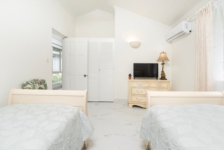 Prostrana spavaća soba 4 sa dva odvojena kreveta, TV-om, klima uređajem, plafonskim ventilatorom i prostranim zajedničkim tuš kabinama.