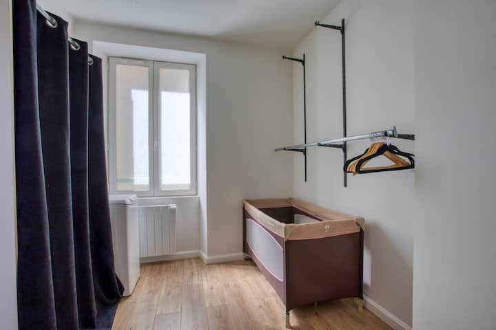 Ett litet rum som har en resesäng och en tvättmaskin 