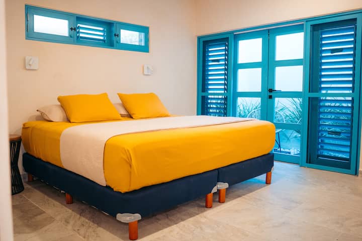 เตียงคิงไซส์ที่อบอุ่นชวนให้คุณดื่มด่ำกับการนอนหลับที่สงบสุขท่ามกลางพื้นผิวธรรมชาติและเสน่ห์ของเขตร้อน