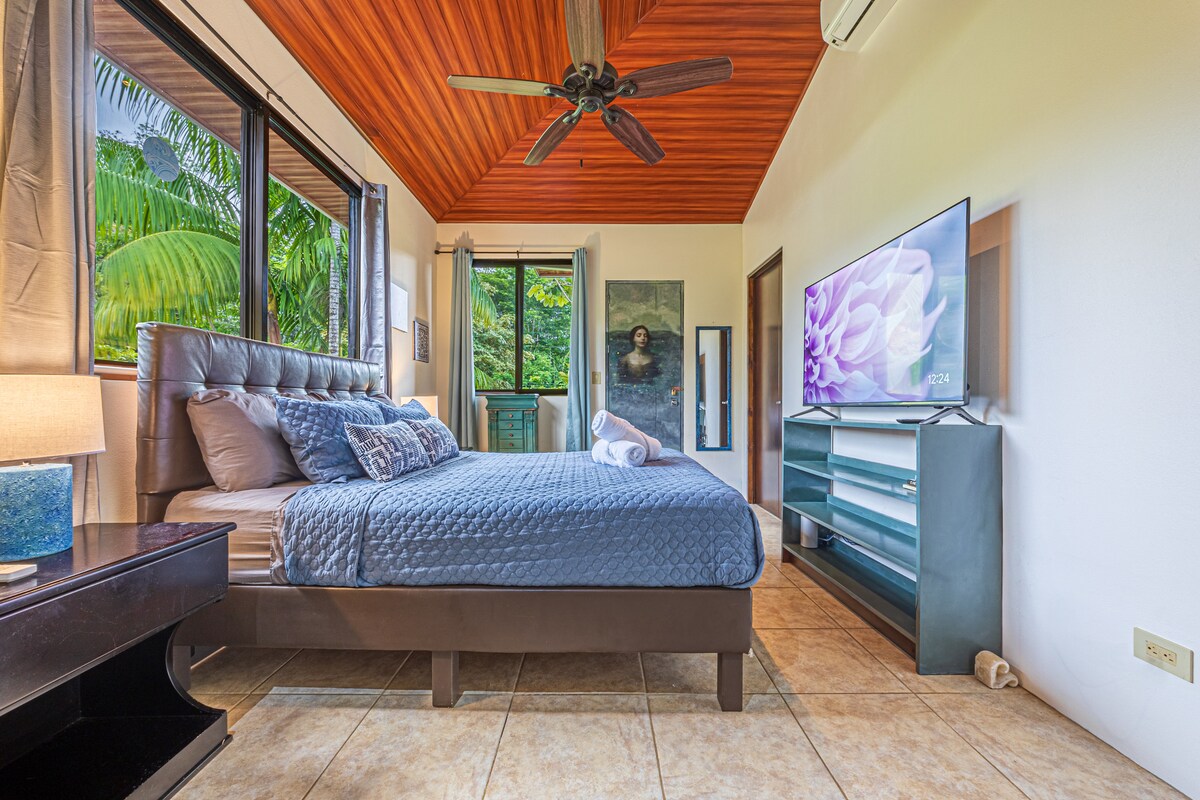 Dormitorio principal con cama tamaño queen, aire acondicionado, ventilador de techo, baño privado, armario y TV inteligente.