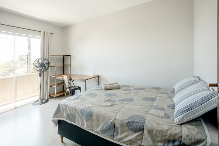 Quarto claro e confortável, com sacada e espaço de trabalho.