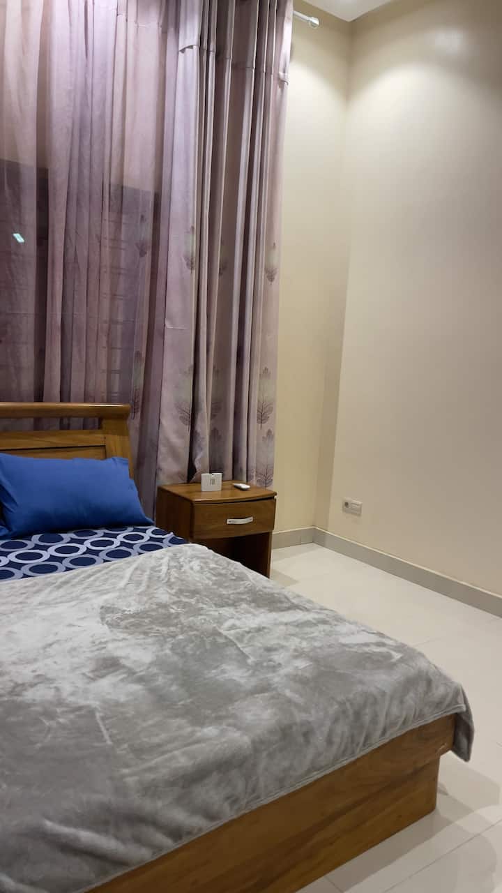Confort des voyageurs : la chambre 2 dispose d'un lit en bois confortable, d'une literie douce et d'une table de chevet dédiée pour plus de commodité. Les rideaux occultants épais assurent une nuit de sommeil privée et reposante.