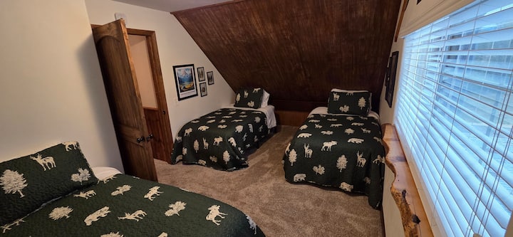 El dormitorio n.º 3 está arriba con 3 camas individuales, un armario grande con 2 cestas de lavandería, un ventilador de suelo oscilante, un calentador de pared y persianas.