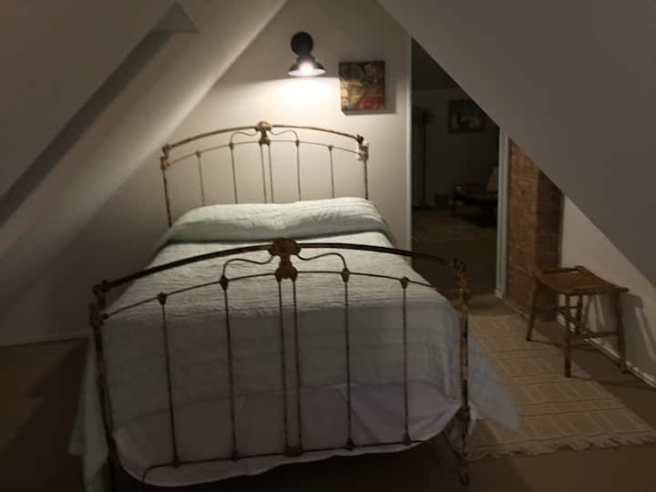 Спална соба со отворен простор, завеси што се користат за приватност.