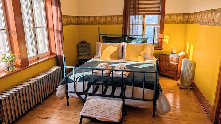 La Miellée room, with its queen-size bed and view of the architecture of the Saint-Damien church