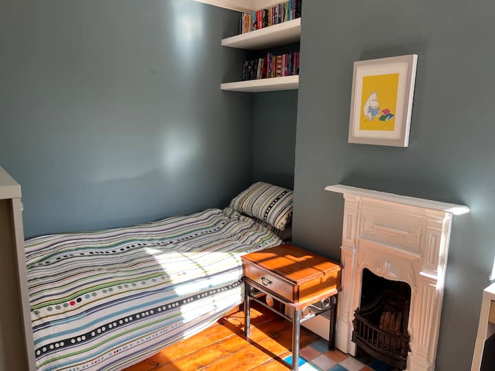 חדר שינה קטן וחמוד עם חלון ענק ורצפת עץ. 