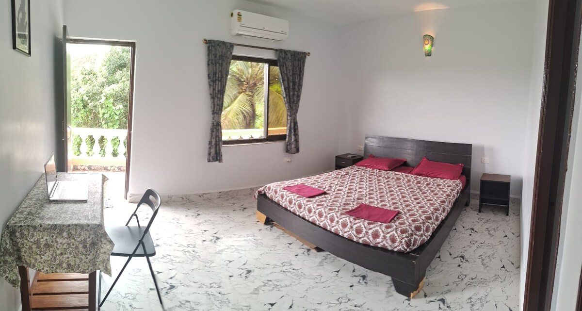 Dormitorio principal luminoso y aireado con una acogedora cama doble, acceso al balcón, aire acondicionado y un espacio de trabajo dedicado, perfecto para la comodidad y la productividad.