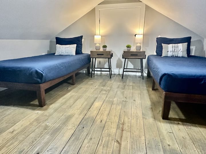 Acogedor espacio loft con dos camas individuales. Un montón de enchufes para cargar, y un ventilador oscilante para una agradable brisa.