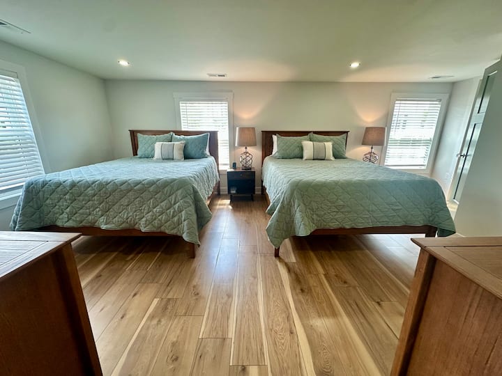 The second bedroom features two queen beds, phone chargers, a TV, Keurig with k-cups, bathrobes and spa slippers, and an ensuite full bath with an assortment of amenities.