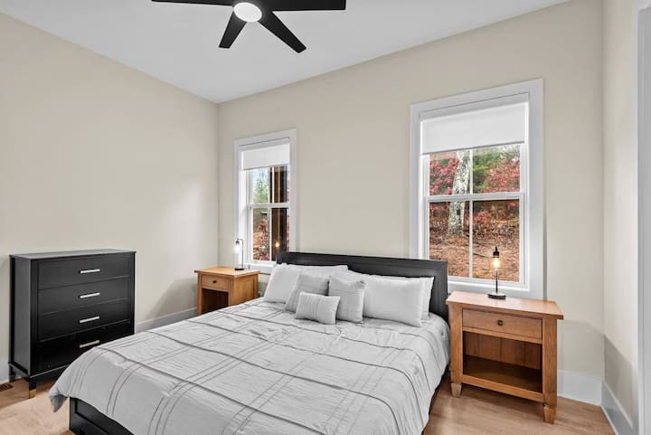 2号卧室配有舒适的标准双人床、两个带灯的床头柜和一个吊扇，让您享受宁静的度假体验。 阳光透过窗户洒落，俯瞰树木繁茂的山坡，在步道或新河上度过一天后，这里是完美的休息之地。