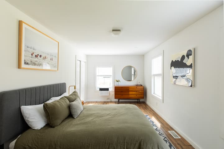 A comfortable, thoughtfully styled queen sized bedroom with natural light 