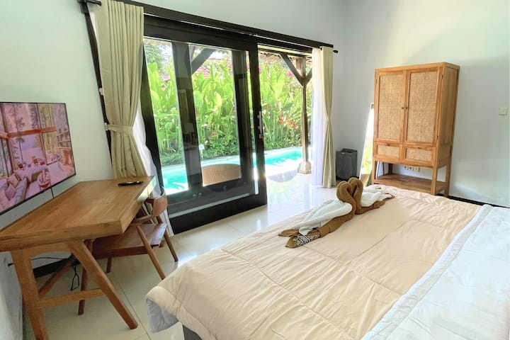 Bedroom with direct pool access and 50 inch Tv workspace — perfect for families or remote stays