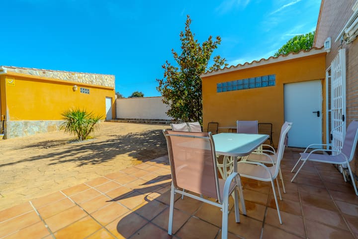 Patio exterior con mesa, sillas y plantas: rincón soleado para relajarse.