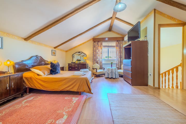 Dormitorio 1 con cama de matrimonio, TV y techo de vigas: amplio y confortable.