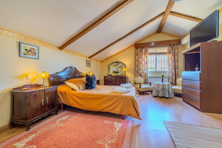 Dormitorio 1 con cama de matrimonio, TV y cómoda bajo el techo de vigas: cálido y espacioso.