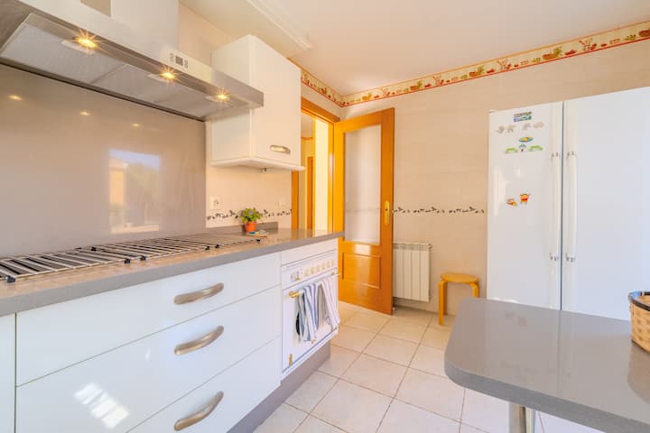 Cocina con nevera grande y amplia encimera: práctica para estancias en familia.