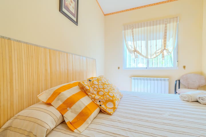 Detalle del dormitorio 4 con cama vestida en tonos cálidos y ventana: tranquilo y agradable.