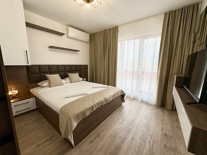 Svijetla spavaća soba s velikim krevetom, ormarom, televizorom i klima-uređajem za udobnost. Francuska vrata osiguravaju prirodno svjetlo i izravan pristup terasi, stvarajući ugodan i srdačan prostor za odmor i opuštanje.