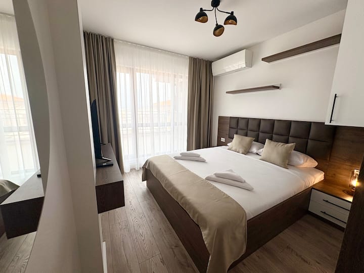 Svijetla spavaća soba s velikim krevetom, ormarom, televizorom i klima-uređajem za udobnost. Francuska vrata osiguravaju prirodno svjetlo i izravan pristup terasi, stvarajući ugodan i srdačan prostor za odmor i opuštanje.