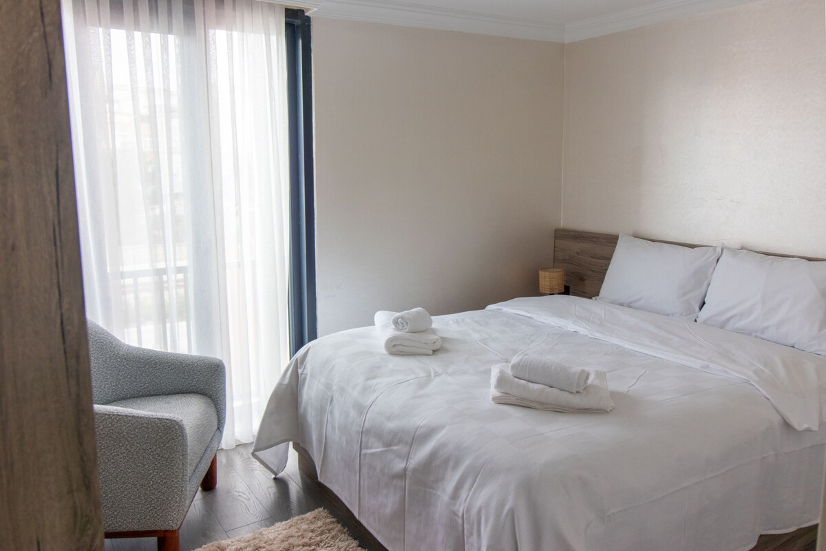 Comfortabele slaapkamer met zacht daglicht en zithoek.