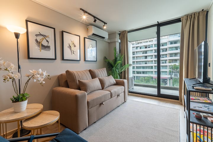Udoban dnevni boravak u modernom stilu: uživajte u svijetlom i elegantnom prostoru s udobnim kaučem, minimalističkim ukrasima i izravnim izlazom na balkon s pogledom na grad. Odlično za opuštanje nakon dana aktivnosti u Santiagu.